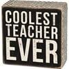 A classic black and white wooden box sign featuring a distressed "Coolest Teacher Ever" sentiment